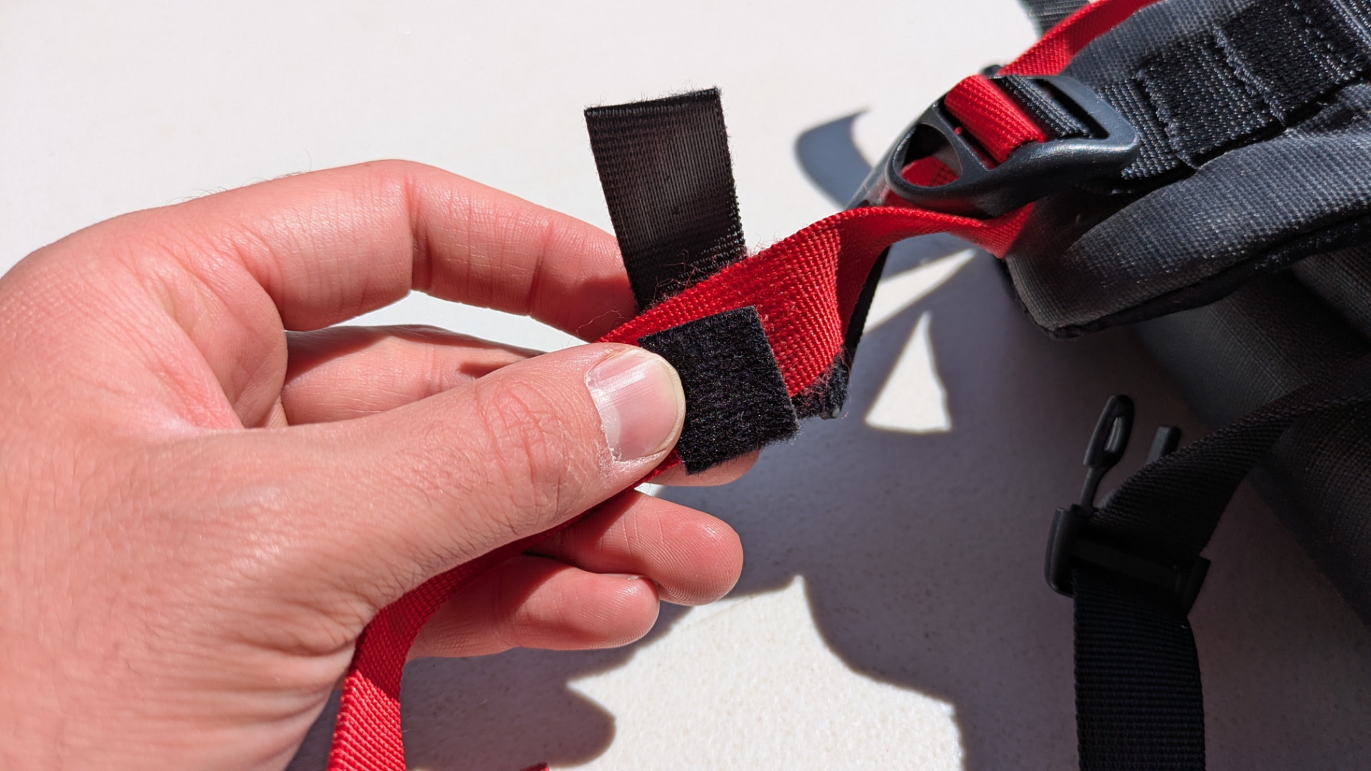 Hands folding the Velcro pieces into a loop around a pack adjustment strap